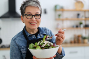 pretty adult woman in glasses eating fresh summer salad. healthy food and vegetarianism concept.